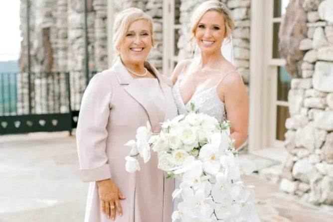 A mother of the bride wearing a Joyce Young teal cape outfit at a wedding venue